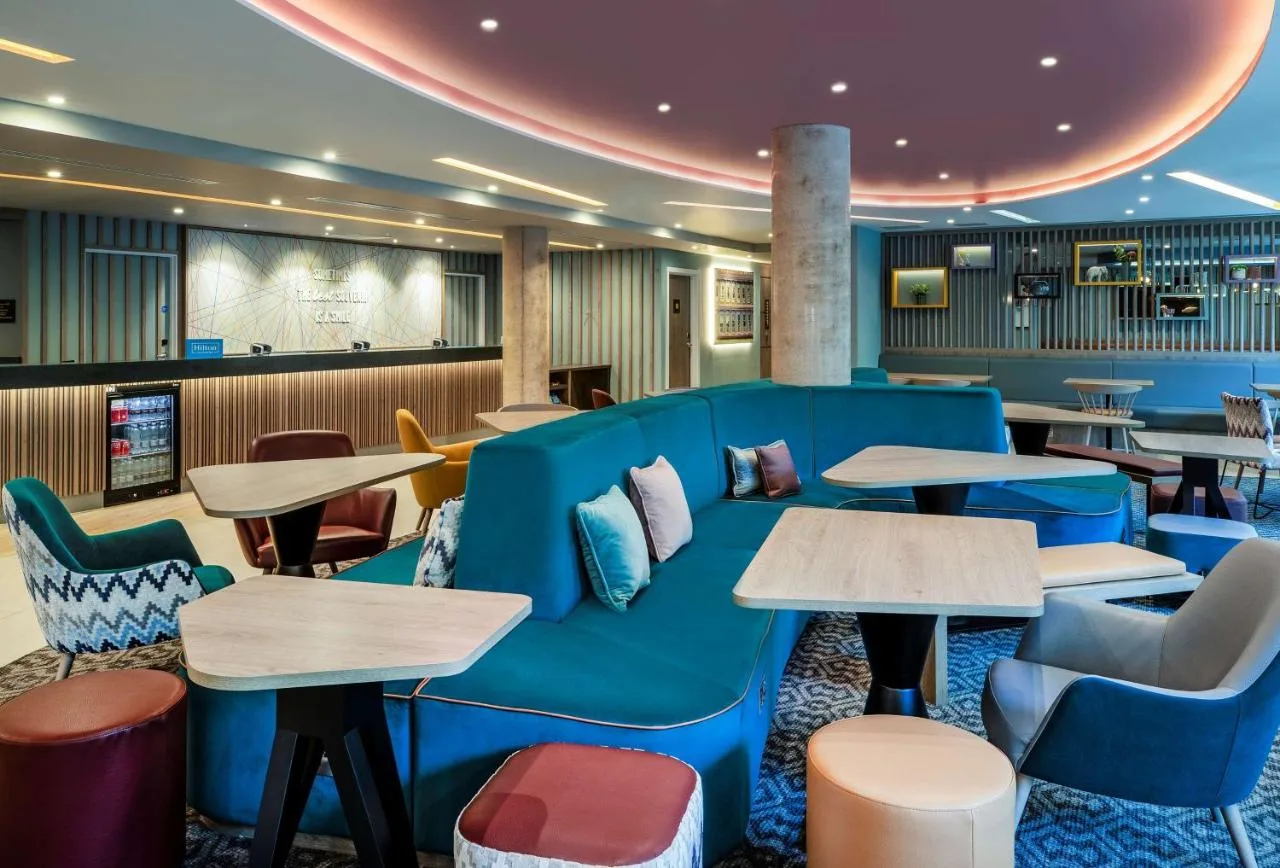 a lobby with a blue couch and tables at Hampton By Hilton Bath City in Bath